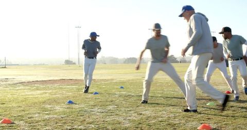 Baseball Team Practicing Speed Drills on Dewy Field with Coach Guiding Players