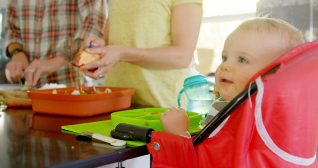 Baby in High Chair Watching Parents Prepare Meal in Kitchen - Download Free Stock Images Pikwizard.com