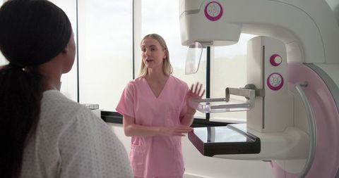 Mammography technician explaining breast screening procedure to patient in clinic