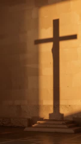Sun casting cross shadow on stone church wall at dawn — vertical contemplative video