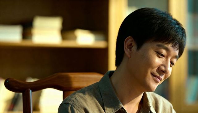 Contemplative asian man reflecting in warm study light, peaceful intimate close-up portrait