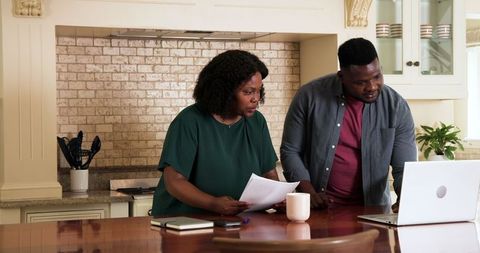 Couple Discussing Finances at Kitchen Table with Laptop