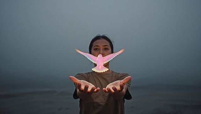 Releasing iridescent dove over open palms, woman standing in misty plain embracing peace