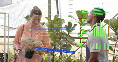 Nursery worker inspecting plants with visitor using augmented reality analytics overlays in greenhou