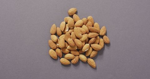 Raw whole almonds on neutral grey backdrop for healthy eating