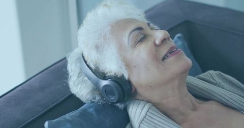Senior woman with headphones relaxing on couch
