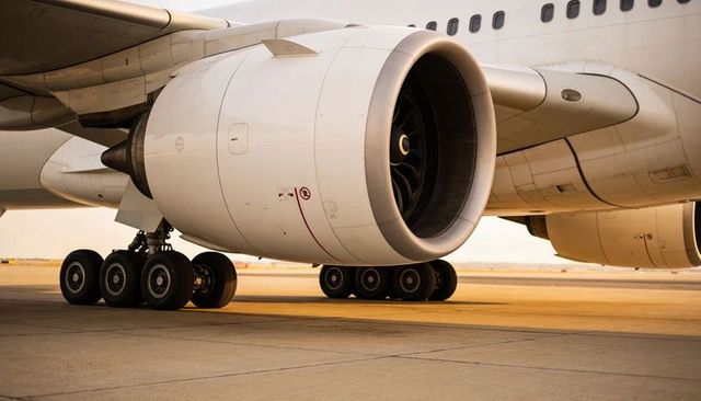 Close-up airliner turbofan engine and multi-wheel landing gear on airport tarmac at golden hour
