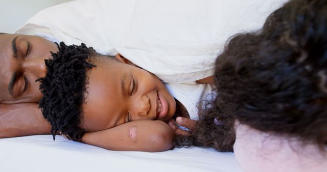 African American parents and child resting together under cozy blankets. Ideal for parenting blogs, advertisements about family time, healthcare, and any content promoting love and togetherness.