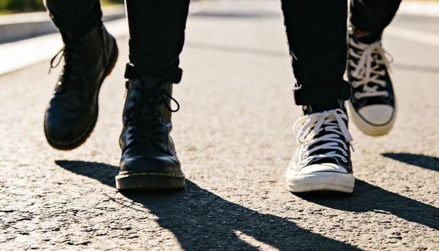 Friends walking on sunlit asphalt wearing combat boots and high-top canvas sneakers