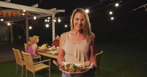 Portrait of happy caucasian mother carrying dish to family dinner table in garden, copy space - Download Free Stock Photos Pikwizard.com