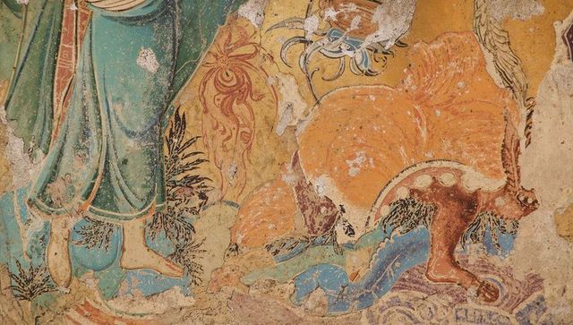 Weathered silk road mural featuring teal-robed figure and orange mythic feline on plaster