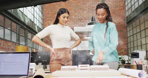 Designers Collaborating Over Architectural Scale Model and Blueprints in Industrial Studio