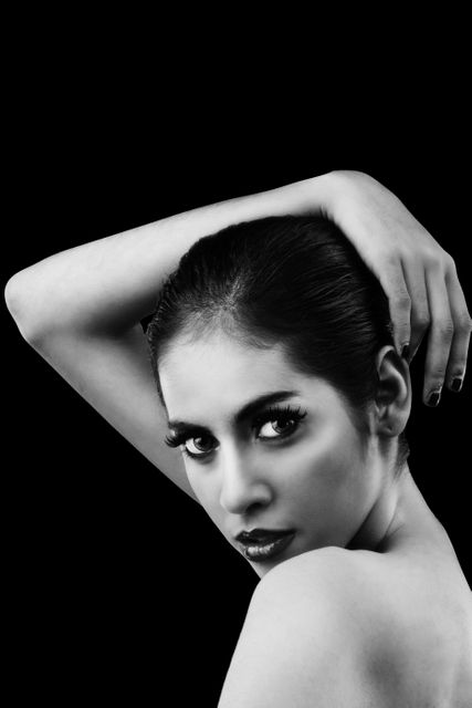 Elegant woman posing with hand on head, showcasing beauty and confidence in a black and white close-up. Suitable for fashion magazines, beauty campaigns, cosmetics advertisements, and stylish editorial content.