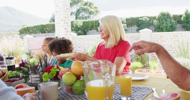 Multi-generational family enjoying an outdoor breakfast. Ideal for content related to family gatherings, quality time, and multiculturalism. Use in ads for food products, lifestyle blogs, and community-focused materials.