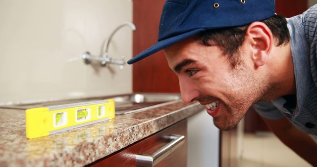 This image showcases a young builder using a spirit level to check the alignment of a countertop. Ideal for content on home improvement, renovation projects, professional construction services, and DIY tutorials.