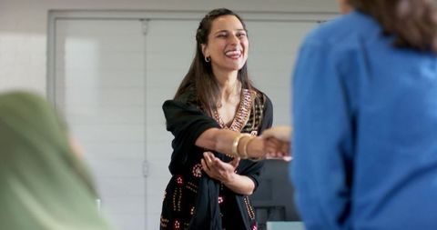 Smiling diverse woman greeting and shaking hands during professional networking meeting