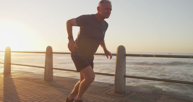 Senior man running along oceanfront at sunset, promoting active lifestyle and fitness in older age. Image useful for promoting health, fitness gear, senior wellness programs, and coastal tourism.