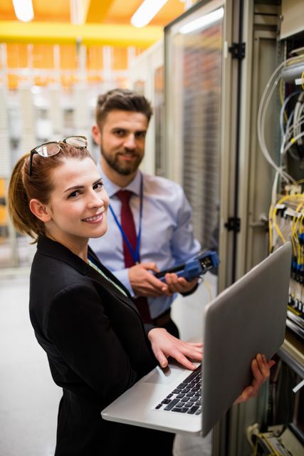 Portrait of technicians using laptop while analyzing server in server room