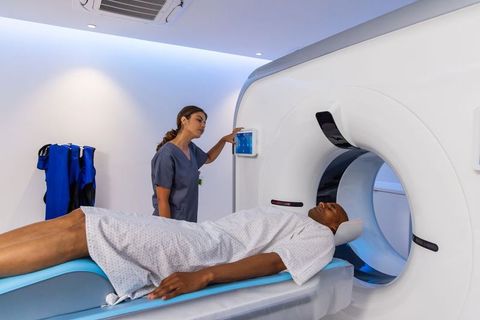 Ct technologist operating modern scanner while patient lying supine on gantry table