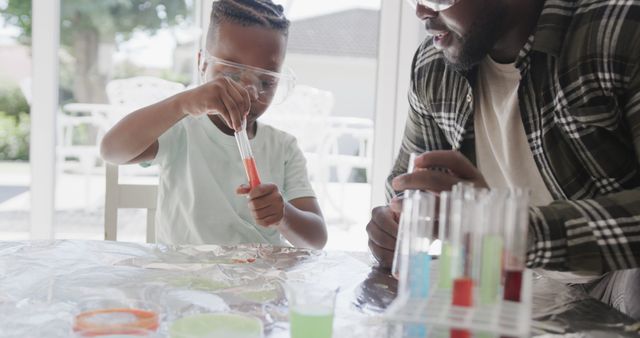 African American father teaching science to his son at home using test tubes and colorful liquids. Both wearing safety goggles, engaging in fun and educational STEM activities. Great for use in educational content, parenting articles, family bonding visuals, and promotional materials for science kits.
