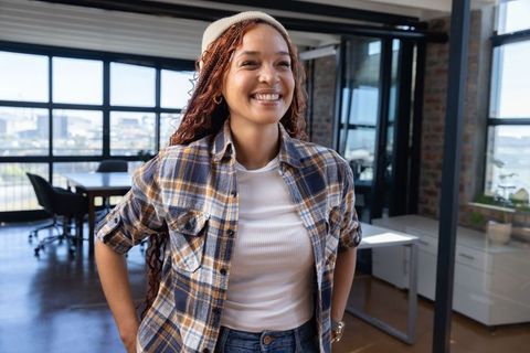 Confident woman in modern office smiling near glass partition