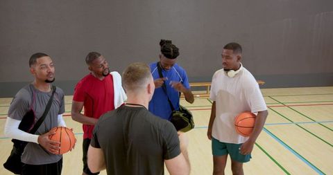 Coach leading basketball team huddle during gym practice players listening attentively