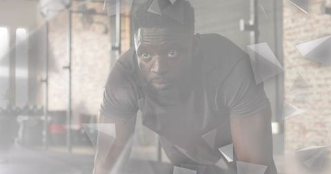 Focused male athlete performing plank in industrial gym with sunlit brick interior