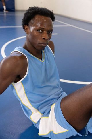 Determined Teen Athlete Resting on Basketball Court in Blue Jersey