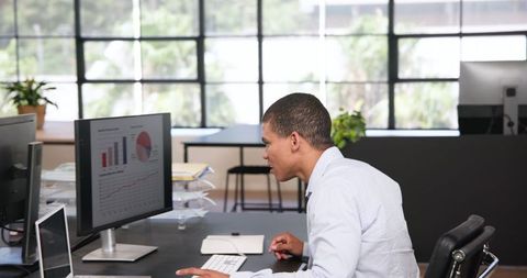 Focused Businessman Analyzing Data on Computer Monitor in Office