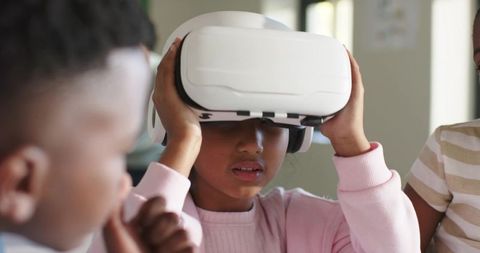 African children exploring virtual reality in classroom while girl adjusts vr headset