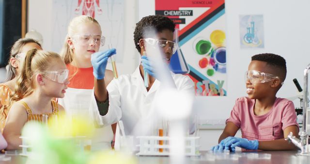 Group of children wearing safety goggles and gloves participate in a science experiment led by a teacher. Ideal for educational materials, school brochures, scientific publications, and diversity in STEM initiatives.