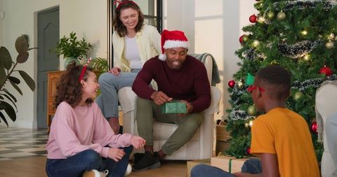 Diverse Family Opening Gifts by Christmas Tree in Cozy Living Room