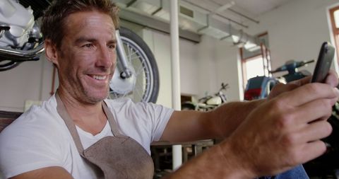 Mechanic Engaged with Smartphone in Workshop