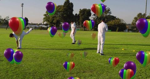 Cricket players stretching during colorful balloon training on sunny green field showing teamwork