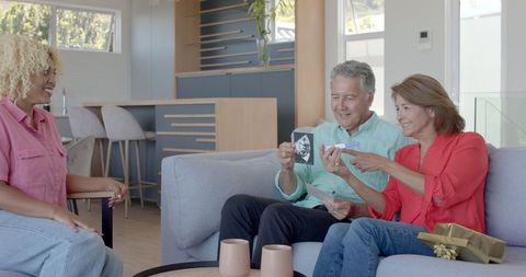 Senior Couple Receiving Gift from Young Woman in Cozy Home Setting