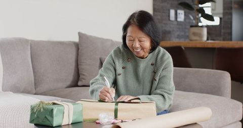 Woman wrapping gifts in cozy living room