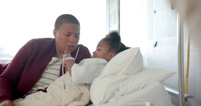 Concerned mother comforting her child lying in a hospital bed. Child connected to an IV. This image can be used in healthcare and parenting contexts, promotions for medical facilities, or articles about family support and child health.