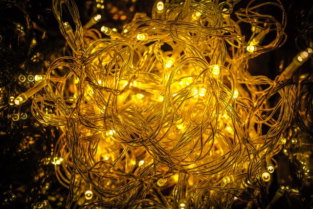 Close-up of intertwined fairy lights glowing warmly, ideal for use in holiday-themed designs, festive event decorations, and creating a cozy atmosphere in interiors. Perfect for Christmas decorations, party invitations, seasonal advertisements, and greeting cards.