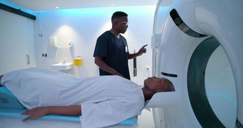 Male radiology technician positioning patient for ct scan in modern hospital suite