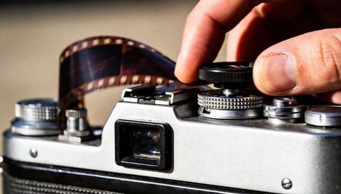 Vintage 35mm film camera knob turning with exposed film strip closeup manual dials