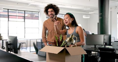 Colleagues unpacking office items together, celebrating new beginnings