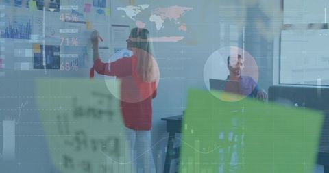 Woman writing on glass wall during team ideation with data overlays and sticky notes