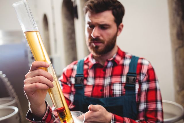 Young manufacturer examining beer in test tube at brewery