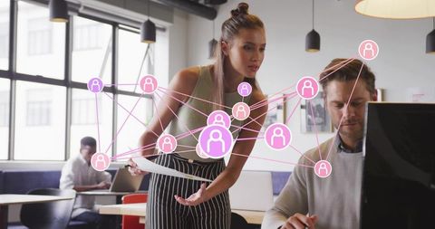 Team collaborating at desktop with pink network overlay showing connected workforce