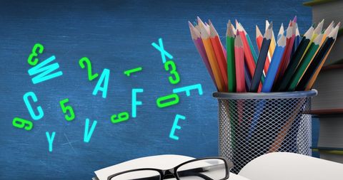 Colorful Crayons in Holder with Scattered Green Letters on Blue Background