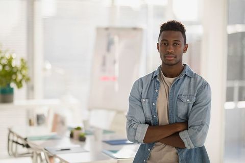 Confident Professional Posing with Arms Crossed in Modern Office