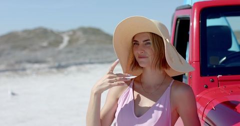 Stylish Woman on Beach Road Trip Posing by Red Car in Summer