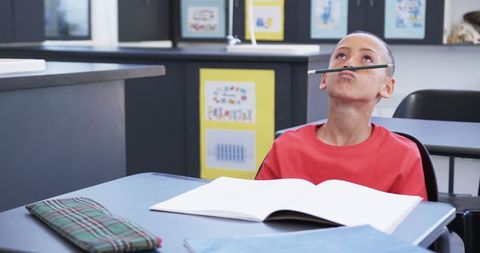 Young boy balancing pencil on lip in classroom amusement