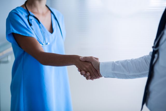 Healthcare professionals shaking hands in a hospital setting, symbolizing teamwork, collaboration, and trust. Useful for illustrating concepts of medical partnership, professional cooperation, and healthcare teamwork in articles, presentations, and marketing materials.