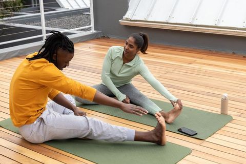 Diverse couple stretching on urban rooftop yoga mats for outdoor fitness and wellness